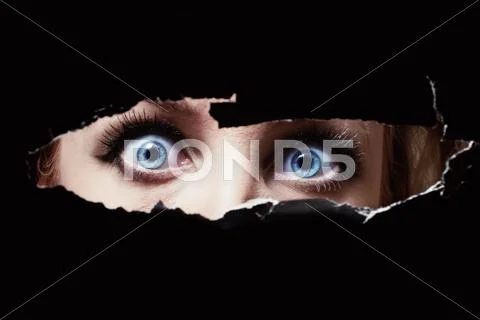 Blue eyes of a young woman peeping Stock Photos