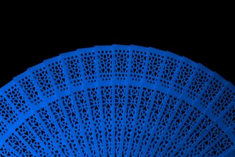 Blue fan with openwork pattern isolated on black background close-up Stock Photos
