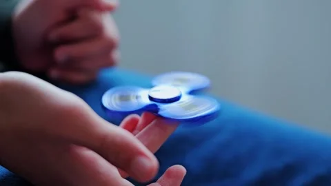 Blue Fidget Spinner Balancing on Finger in Slow Motion Indoor Scene, Soft Light Stock Footage 327774041