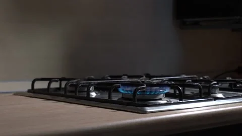 A blue fire burns strongly on a gas stove. female white hands put on a burner Stock Footage 130792837