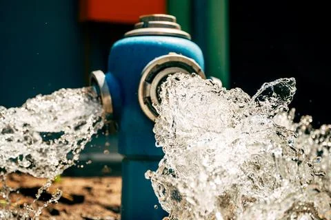 Blue fire hydrant flushing high-pressure water into a street gutter. Munici.. Fotos de archivo