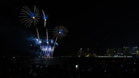 Blue Fireworks Display Exploding Over Coastal City Skyline Wide Shot Stock Photos