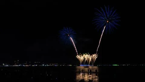 Blue Fireworks Exploding Over Ocean Bay With Silhouette Crowd At Pattaya Beac Stock Photos