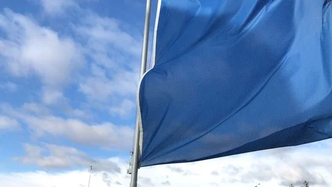 Blue flag waving against blue sky with clouds at windy day Stock Footage 129095208