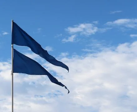 Blue flags flying in wind against blue sky 스톡 사진