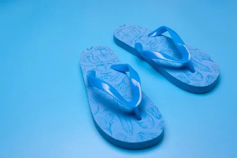 Blue flip flops on a blue background Stock Photos