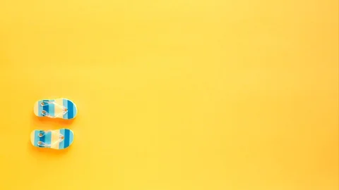 Blue flip-flops walk on a yellow beach. Concept of tourism and recreation Stock Footage 129324974