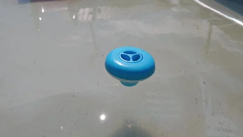 Blue floating chlorine dispenser distributing chemicals in swimming pool Stock Footage 315359863