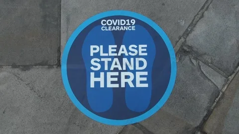 A blue floor pavement social distancing sticker label.  "Please stand here". Stock Footage 132172783