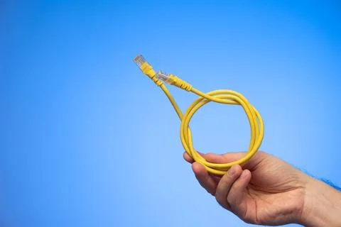 Blue folded Ethernet cable held in hand by Caucasian male hand studio shot is Stock Photos