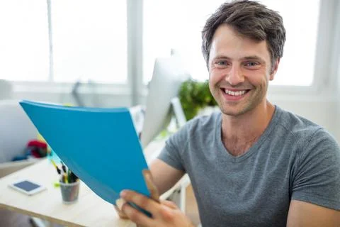 Blue folder resting beside desktop monitor with smartphone and potted plant near Stock Photos