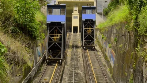 Blue funicular climbing an elevator on a hillside surrounded by bushes and trees Stockbeeldmateriaal 319211534