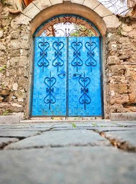 Blue gate with patterned forging on background of facade of old masonry wall Stock Photos