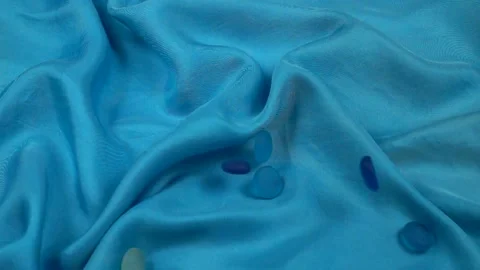 Blue glass elements for decoration fall on turquoise silk fabric, slow motion Stock Footage 295206607