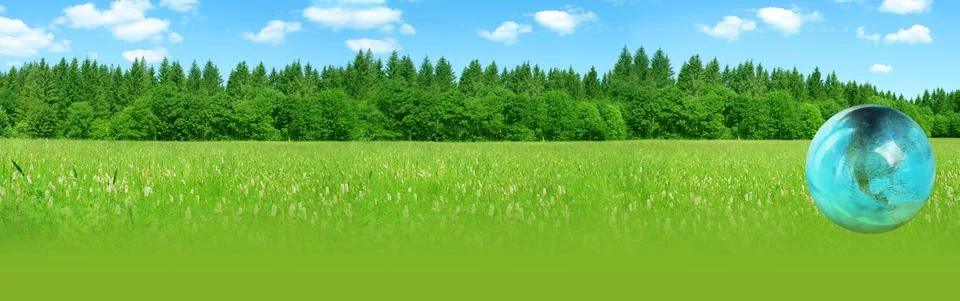 Blue globe, a model of the planet explodes in spray on a green landscape back 写真素材