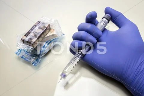 Blue-Gloved Hand Holds A Syringe Of Insulin Together With Some Sweets And Pac