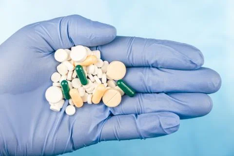Blue-gloved hand pulls a handful of pills Stock Photos