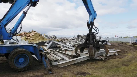 Blue grader puts beams onto pile at arena demolition site Stock Footage 127740896