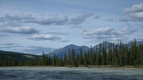 Blue-grey clouds move slowly across the sky with a large river in the foreground Stock Footage 139163265