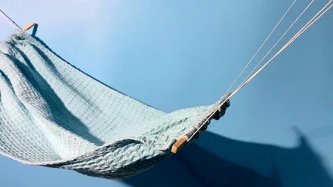 Blue hammock swinging on a blue background Stock Footage 220261726