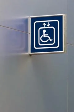 Blue handicap elevator sign on metallic wall with below copy space Stock Photos