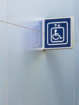 Blue handicap elevator sign on metallic wall with copy space Stock Photos