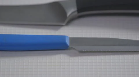 Blue handle knife on a white surface; pan Stock Footage 64030101