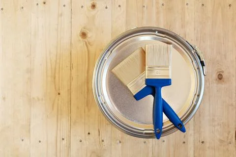 Blue-handled paintbrushes on a paint can lid on a light wooden background, Stock Photos