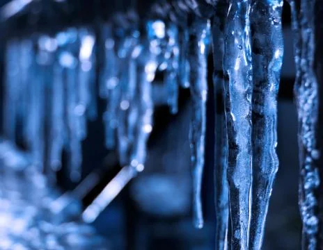 Blue hanging icicles with blurred background Stock Photos
