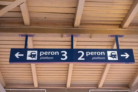 A blue hanging navigation sign at a train station indicates directions to Stock Photos