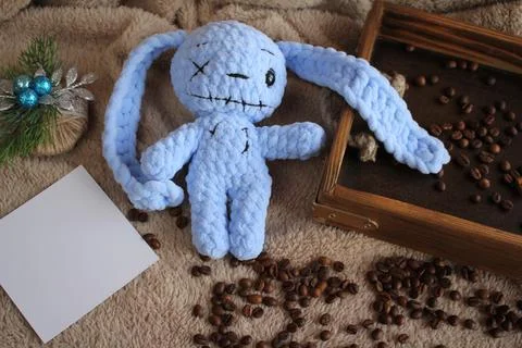 The blue hare lies on a table on a plush blanket. There is a wish card next to Stock Photos
