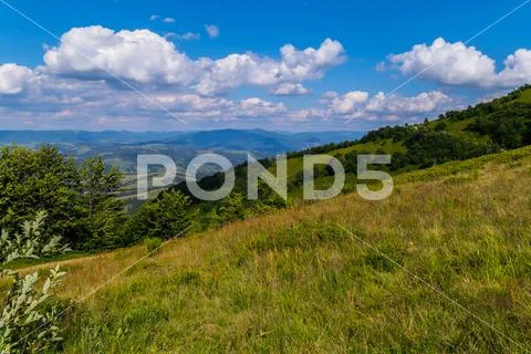 Blue of the heavenly ocean with slowly floating clouds over the mountain vall Stock Photos