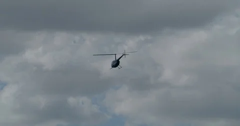 Blue helicopter flying away in cloudy sky Stock Footage 94331973