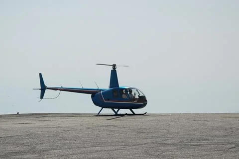 Blue helicopter flying in grey cloudy skies Foto stock