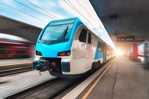 Blue high speed train in motion on the railway station at sunset. Fast mode.. Stock Photos