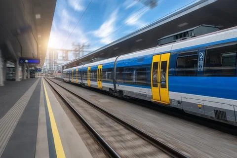 Blue high speed train in motion on the railway station at sunset Stock Photos