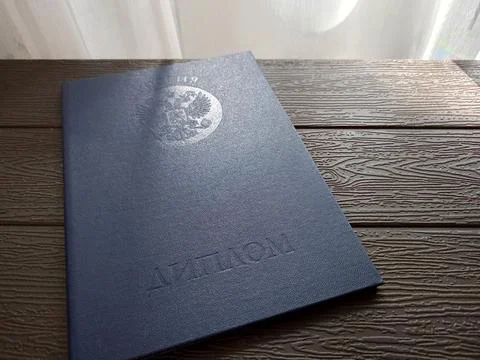 A blue higher education document on a table by a window Stock Photos