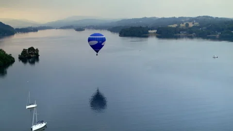 Blue hot air balloon flying over a calm lake at dawn Stock-Footage 336807634