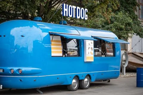 Blue hot dog van on empty street in city, mobile food truck. Cafe in transport Stock Photos