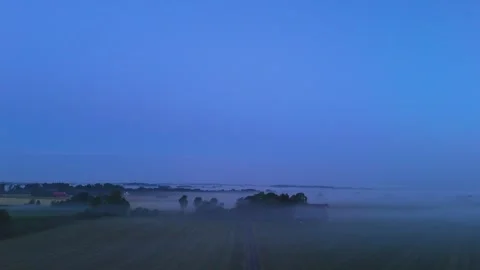 Blue hour mist drifting across rural farmland with distant wind turbines Stock Footage 341036083
