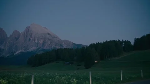 Blue Hour over the Dolomites Featuring a Car Passing Through Alpine Meadow Stock Footage 331164215