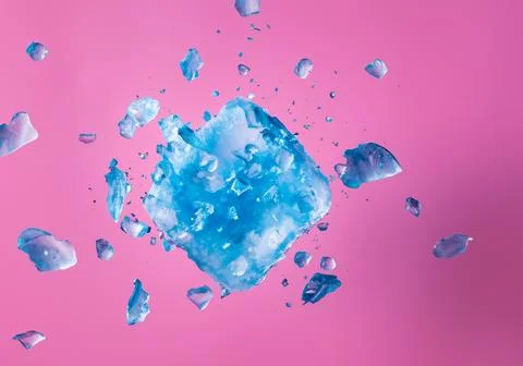 Blue ice block exploding into shards on pink pastel background Foto stock