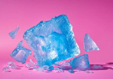 Blue ice block exploding into shards on pink pastel background Stock Photos