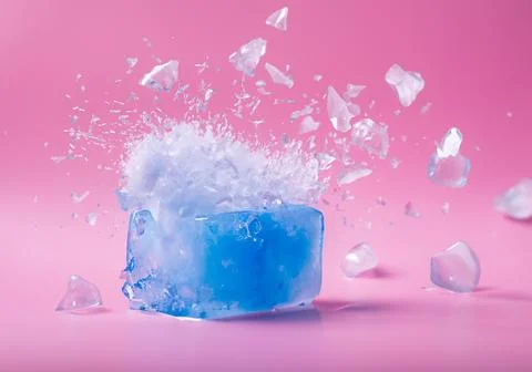 Blue ice block exploding into shards on pink pastel background Stock Photos