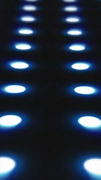 Blue illuminated circles in a grid pattern glowing over a dark surface, creat Stock Photos