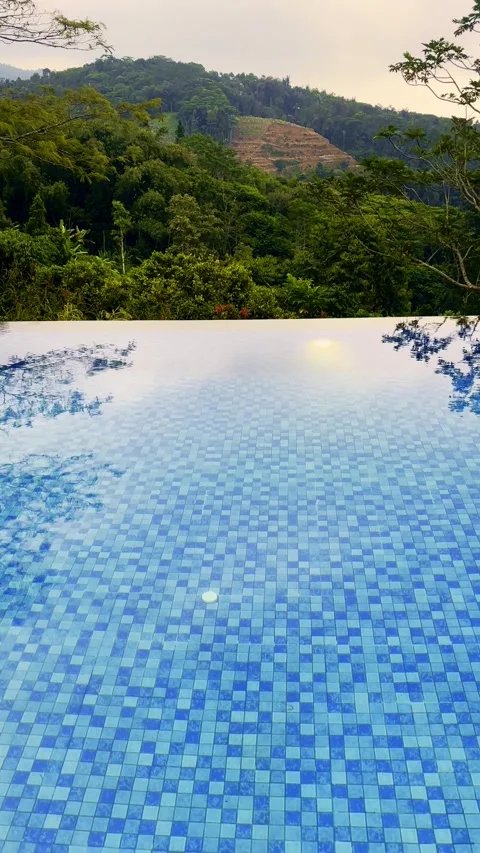 Blue infinity pool overlooks lush forested hills at a tranquil tropical mou.. Stock Footage 340116031