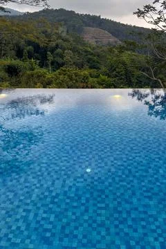 Blue infinity pool overlooks a lush forested mountain landscape at a peacef.. Stock Photos