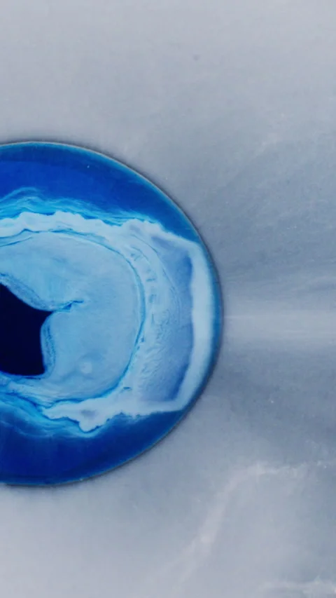 Blue ink bloom forming organic circular pattern on white background vertical Stock Footage 341232021