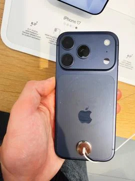Blue iPhone 17 held in hand displaying triple camera setup and sleek back d.. Stock Photos