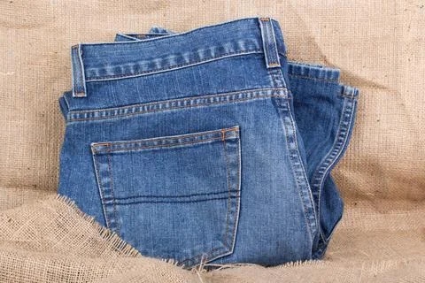 Blue jeans on burlap Stock Photos
